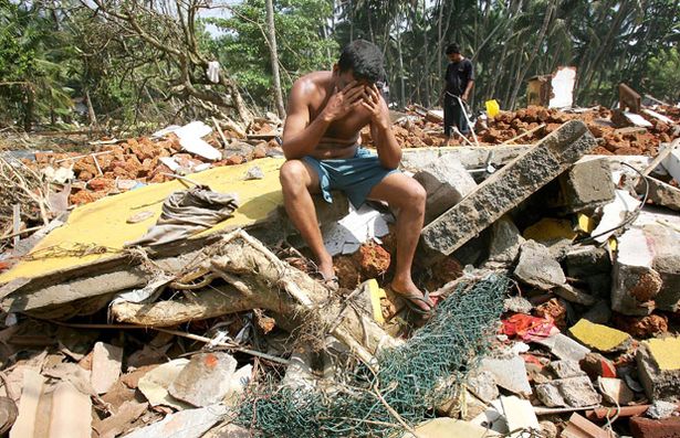 A Sri Lankan man despairs as he searches among the ruins of his house devastated by the Boxing Day Tsunami, 2004.